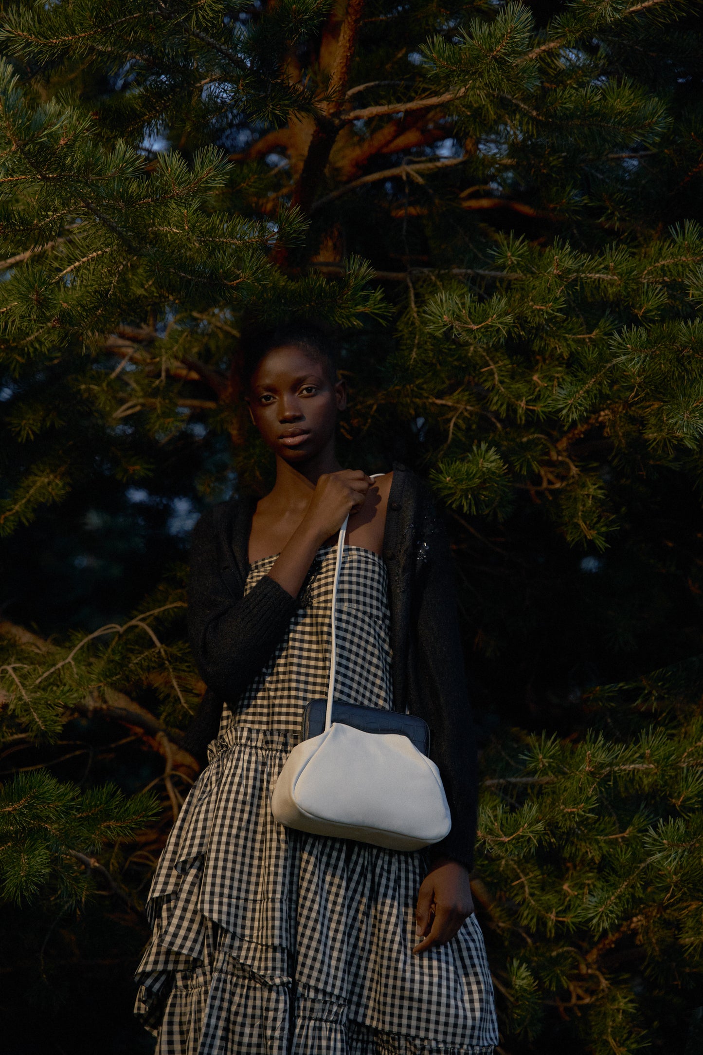 Chica con árbol de fondo sosteniendo un bolso de hombro blanco
