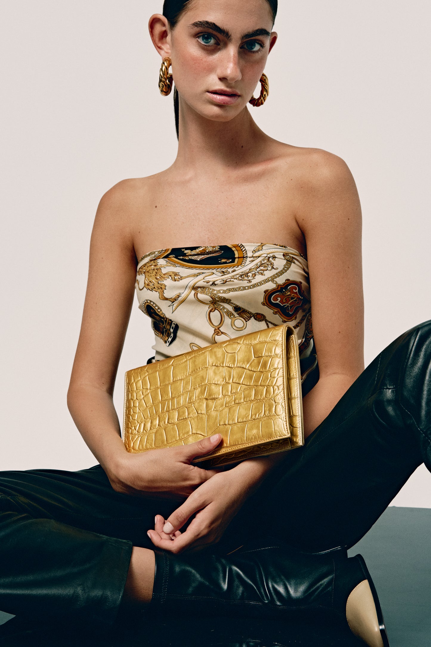 Chica con un bolso de mano metalizado dorado con efecto piel de cocodrilo