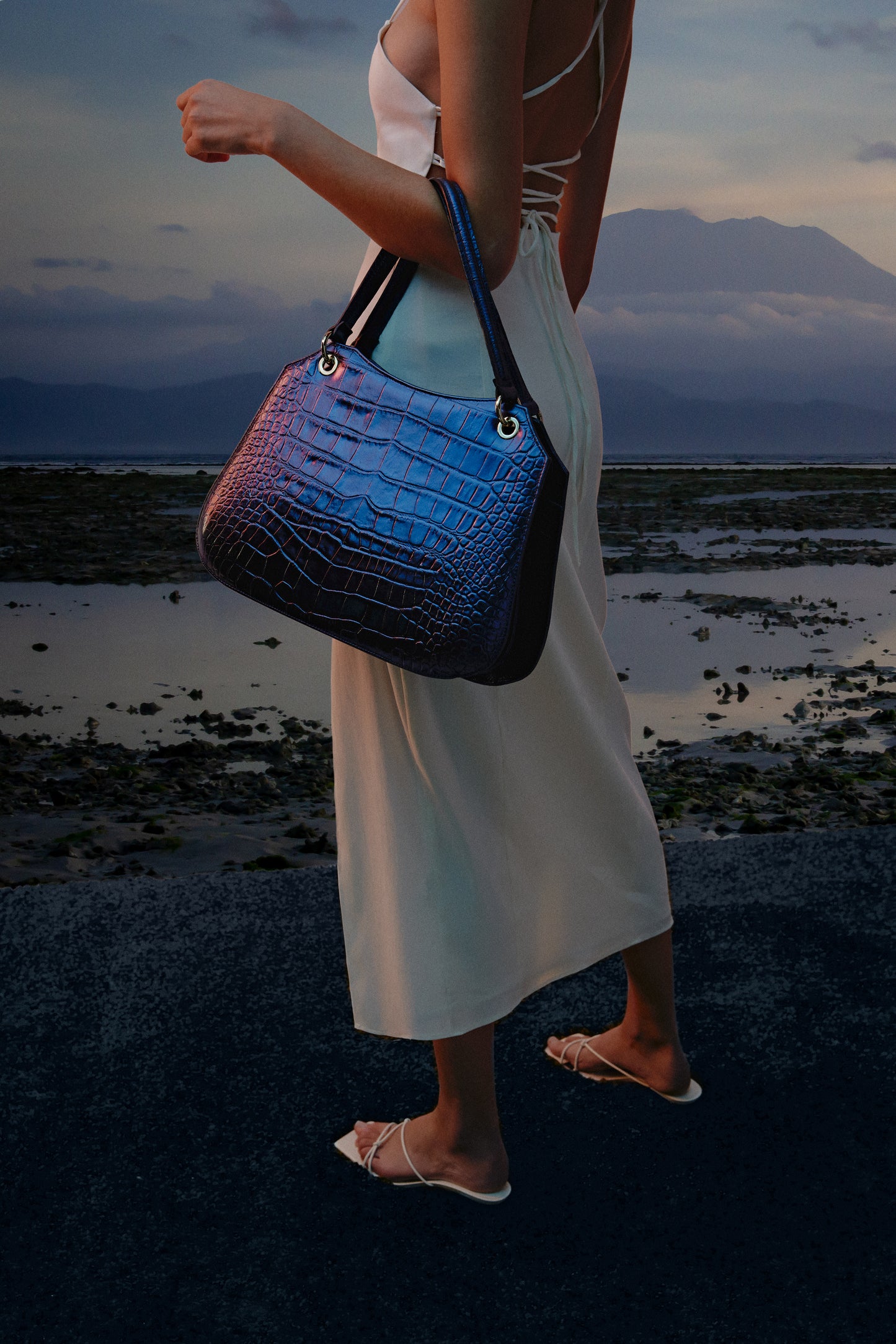 Mujer posando con un bolso de mano azul marino con piel efecto cocodrilo