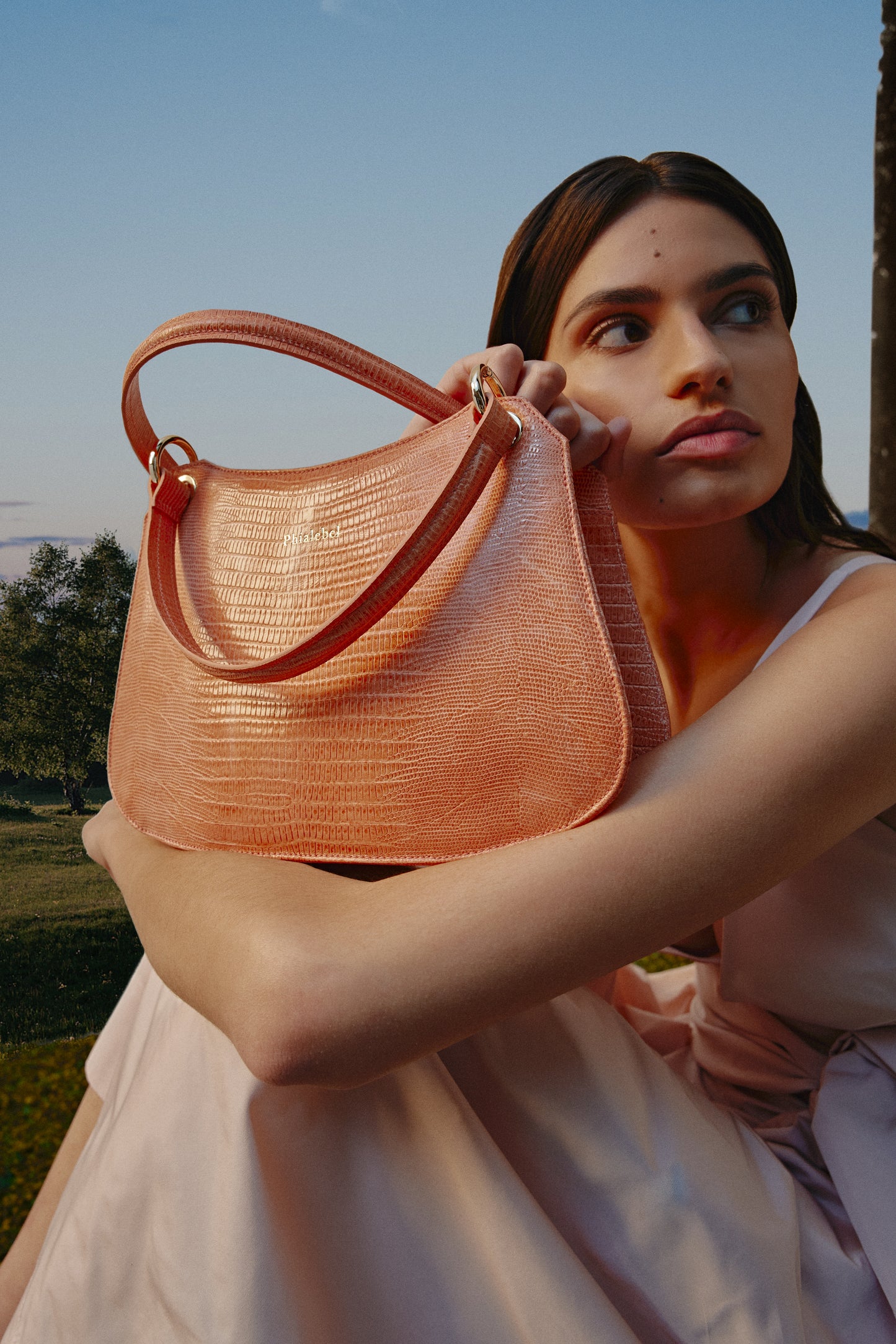 Chica sosteniendo un bolso de mano naranja efecto lizard metalizado