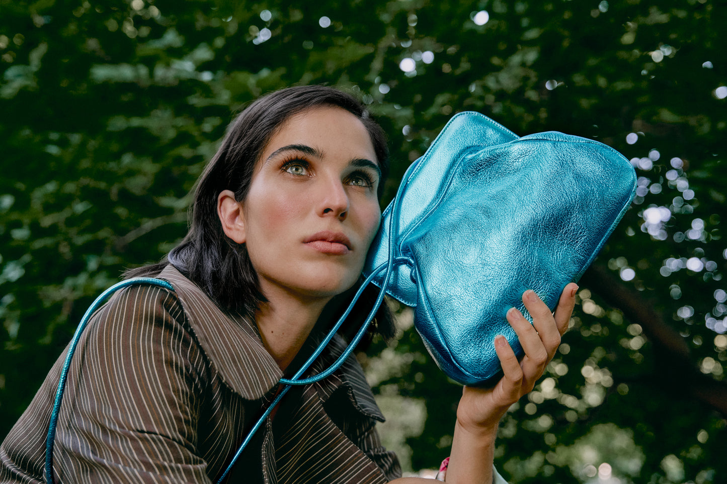 Chica posando con un bolso de mano en azul metalizado