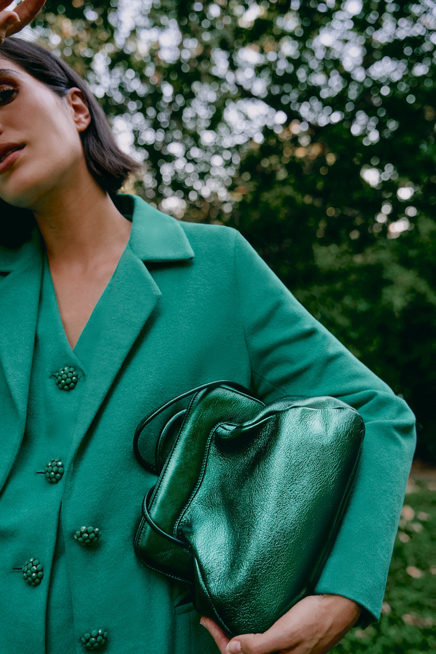 Chica cogiendo un bolso verde en acabado metalizado brillante