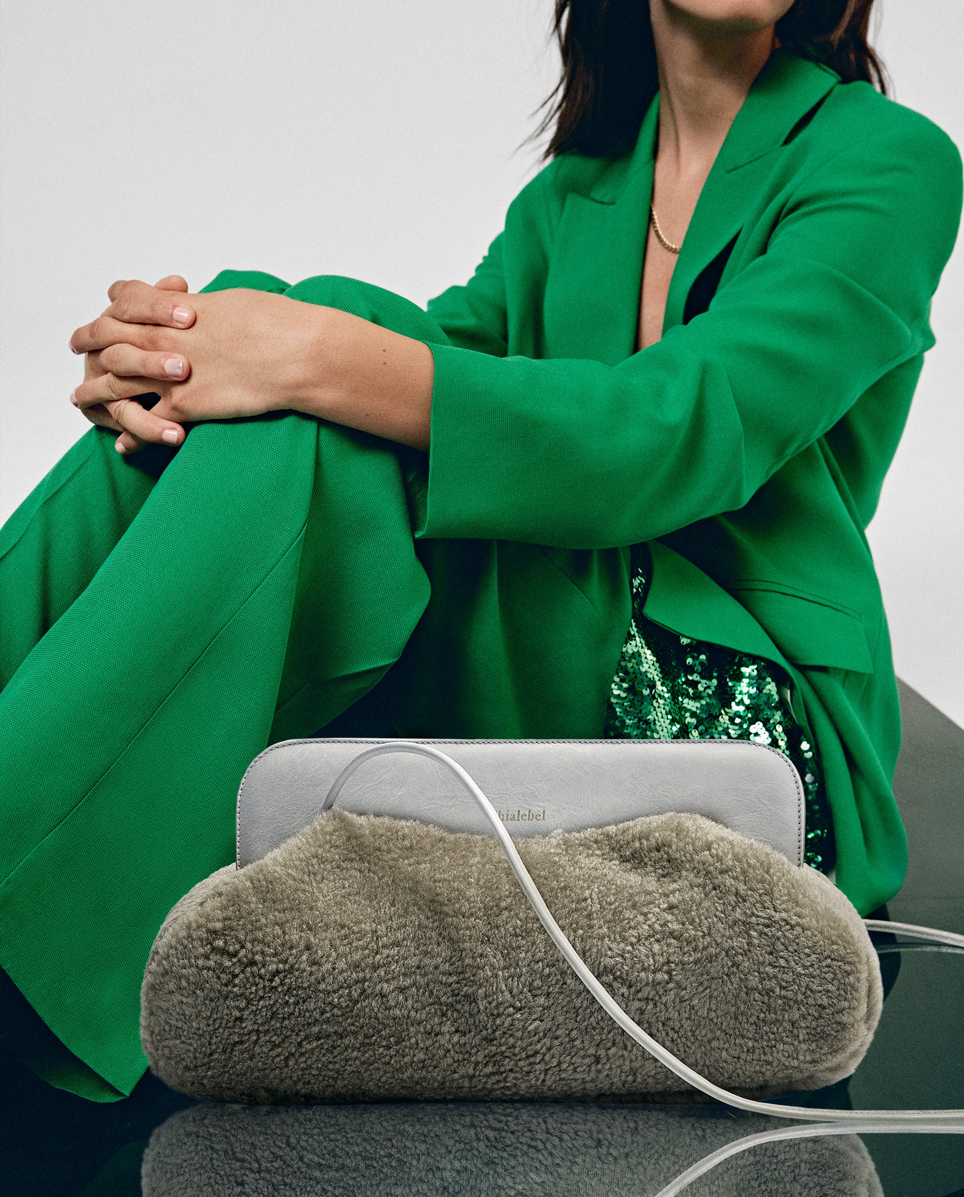 Bolso de hombro borreguito beige junto a mujer con traje verde
