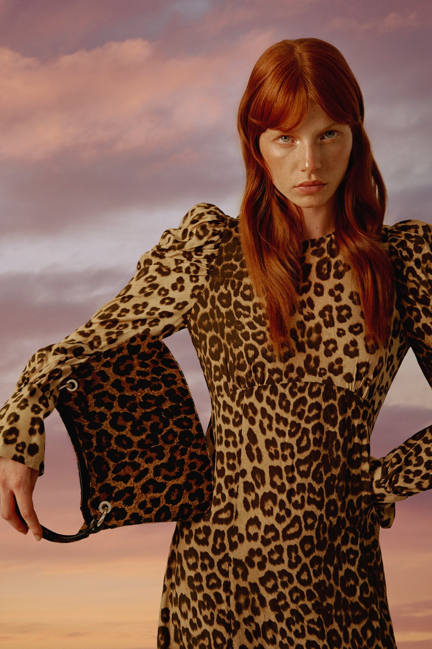 Chica pelirroja con un vestido de leopardo a juego con su bolso de mano