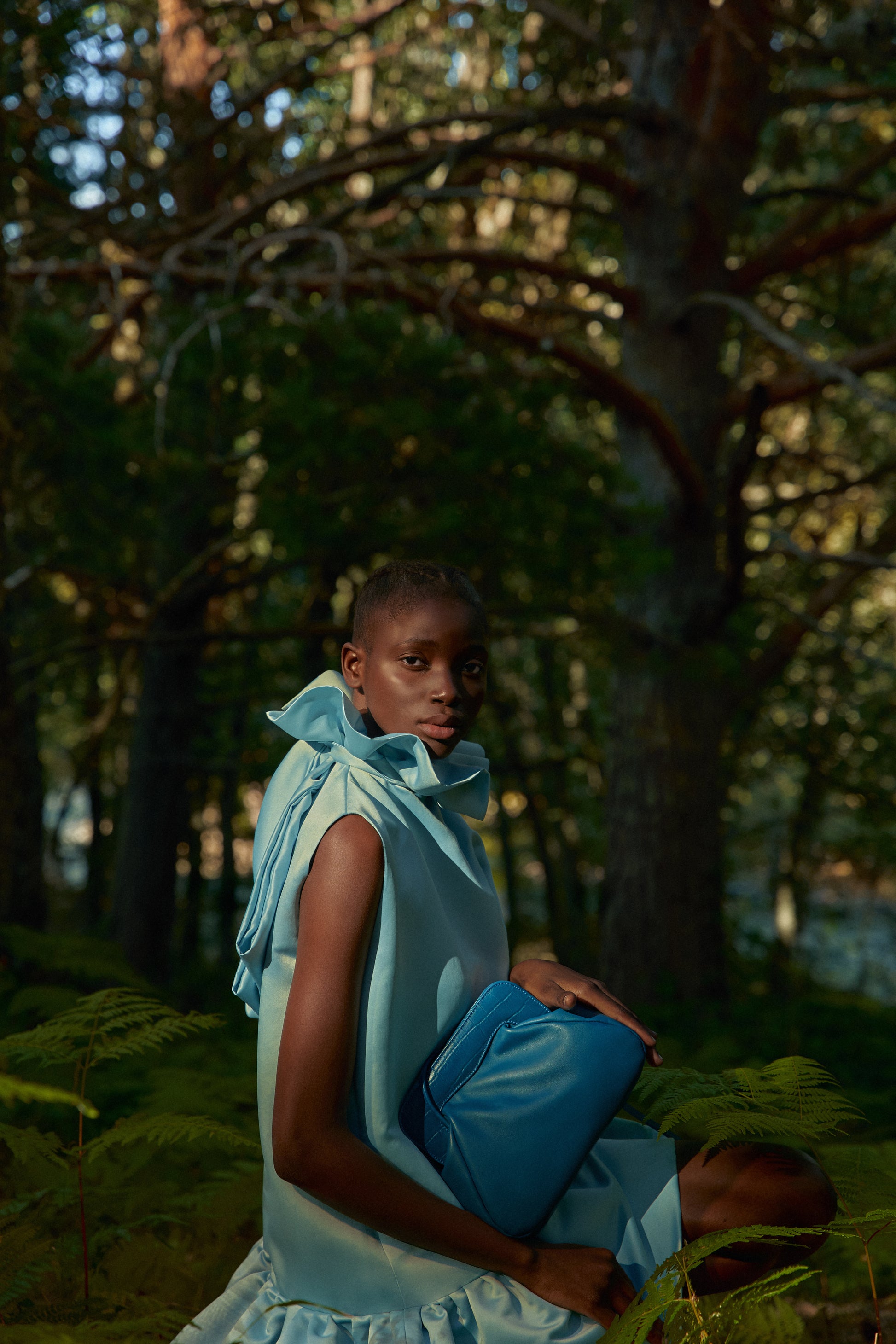 Chica en bosque posando con un bolso azul