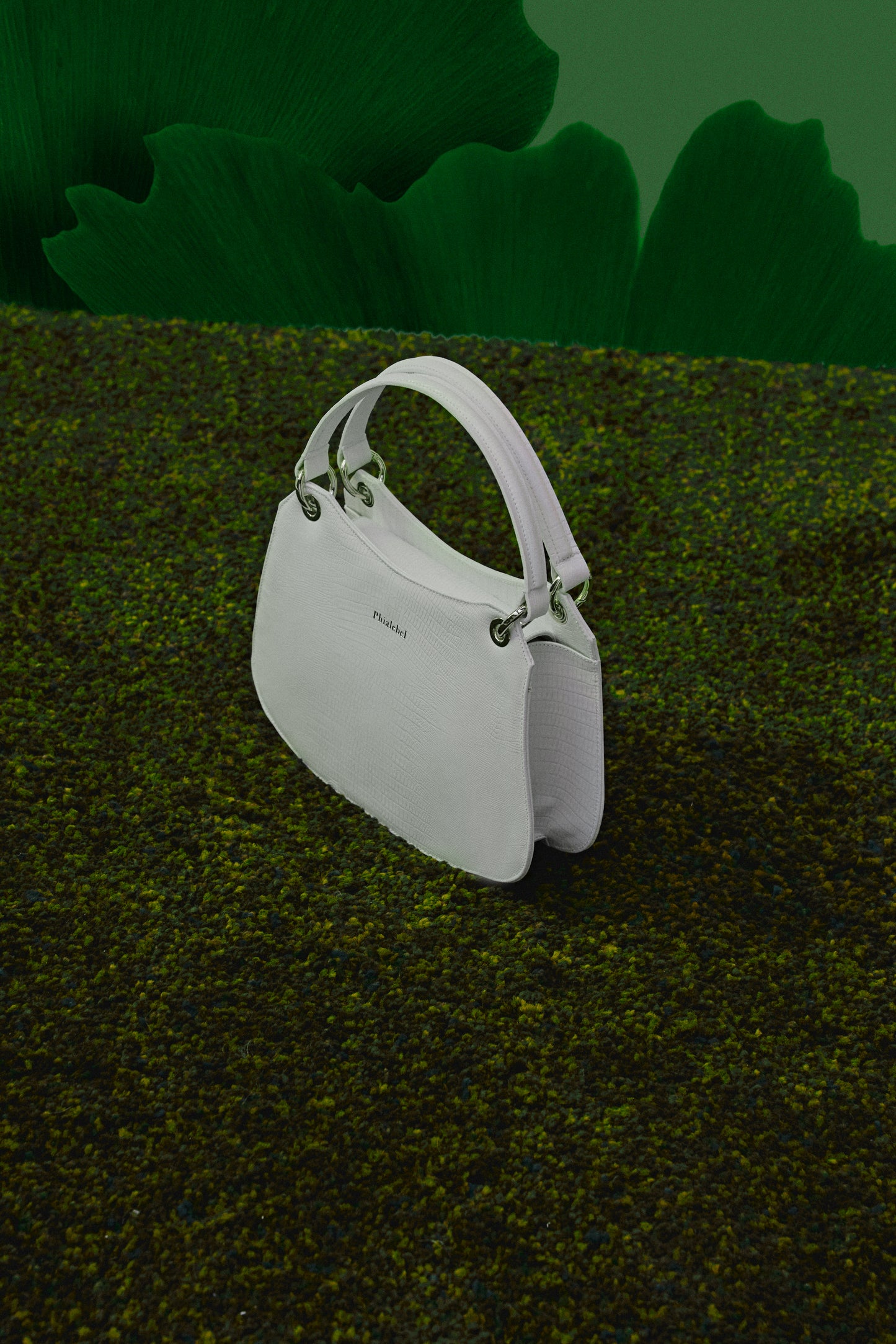 Bolso blanco metalizado puesto sobre la hierba