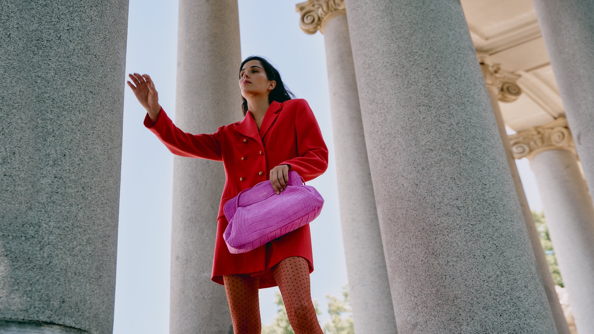 Mujer de rojo sosteniendo un bolso de hombro rosa fucsia efecto cocodrilo