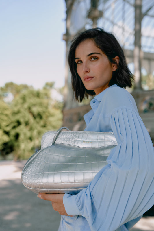 Mujer sosteniendo un bolso de hombro color plata metalizado