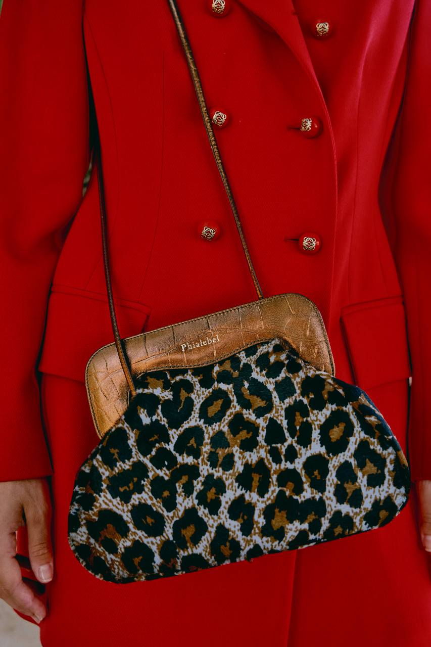 Mujer con abrigo rojo y bolso de leopardo en gris